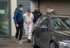 Polizisten bringen einen der Tatverdächtigen (im weißen Overall) nach dem Haftprüfungstermin am Landgericht Kaiserslautern aus dem Justizgebäude. Foto: Harald Tittel/dpa