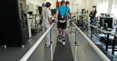 Ein Patient mit kompletter Rückenmarksverletzung geht im Universitätsspital Lausanne nach 5 Monaten Reha. Eine implantierte Folie mit 16 Elektroden gibt kleine elektrische Impulse an Nervenbahnen ab, die zu Motorneuronen in der Wirbelsäule führen. Foto: Jimmy Ravier/NeuroRestore/dpa