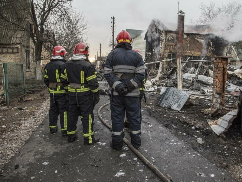 Feuerwehrleute betrachten die Trümmer eines Flugzeugs das zwischen Häusern abgestürzt ist. Es war unklar, wessen Flugzeug abgestürzt ist und wer es zum Absturz gebracht hat. Russische Truppen sollen bis in die Außenbezirke der Hauptstadt vorgedrungen sein. Foto: Oleksandr Ratushniak/AP/dpa