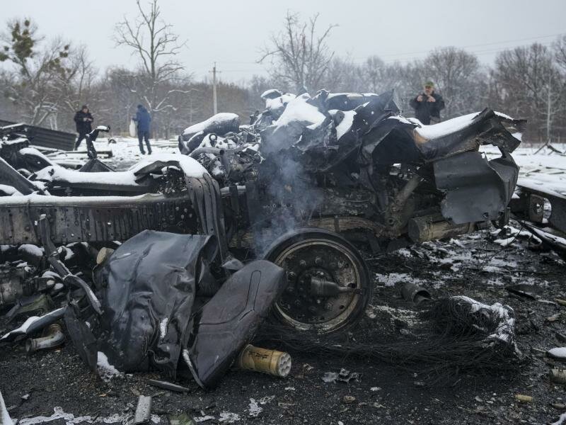 Menschen fotografieren noch schwelende zerstörte russische Militärfahrzeuge am Stadtrand von&nbsp;Charkiw. Foto: Vadim Ghirda/AP/dpa