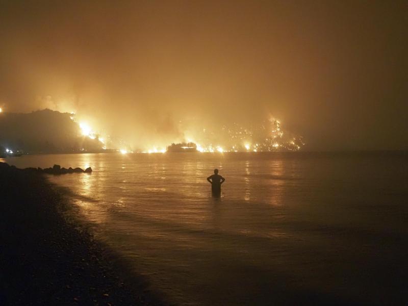 Ein Mann beobachtet im August 2021, wie sich Waldbrände dem Strand von Kochyli in der Nähe des Dorfes Limni auf der Insel Evia (Griechenland) nähern. Foto: Thodoris Nikolaou/AP/dpa