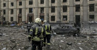 Ukrainische Rettungskräfte arbeiten vor dem beschädigten Rathausgebäude in Charkiw nach dem russischen Beschuss. Foto: Pavel Dorogoy/AP/dpa