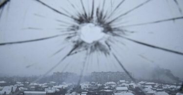 Blick aus einem durch Granatenbeschuss zerbrochenen Krankenhausfenster auf Mariupol. Foto: Evgeniy Maloletka/AP/dpa