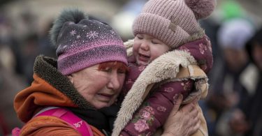 Eine weinende Frau mit einem Kind im Arm am Grenzübergang im polnischen Medyka. Foto: Visar Kryeziu/AP/dpa