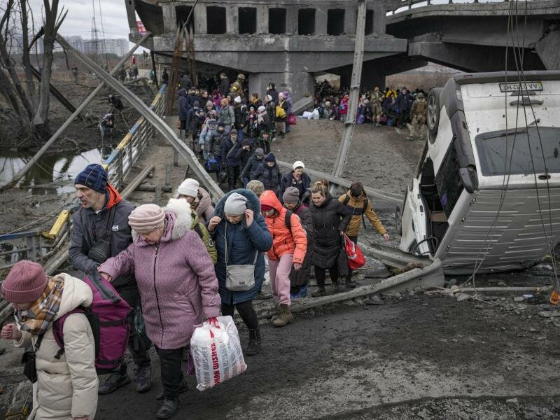 Menschen aus der Ukraine überqueren den Fluss Irpin auf einem improvisierten Weg unter einer zerstörten Brücke. Foto: Vadim Ghirda/AP/dpa