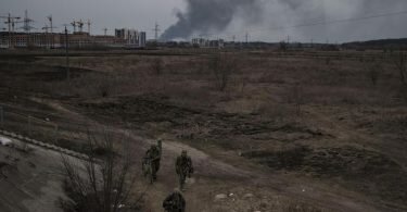 Soldaten gehen einen Weg entlang, während Rauch in Irpin nordwestlich von&nbsp;Kiew aufsteigt. Foto: Felipe Dana/AP/dpa