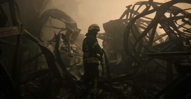 Ein ukrainischer Feuerwehrmann zieht einen Schlauch durch ein großes Lebensmittellager am Stadtrand von Kiew, das durch einen Luftangriff zerstört wurde. Foto: Vadim Ghirda/AP/dpa