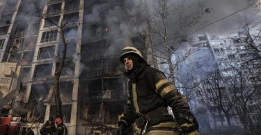 Einsatzkräfte der Feuerwehr stehen in Kiew vor einem brennenden Wohngebäude, dass durch Bombenbeschuss des russischen Militärs zerstört wurde. Foto: Vadim Ghirda/AP/dpa