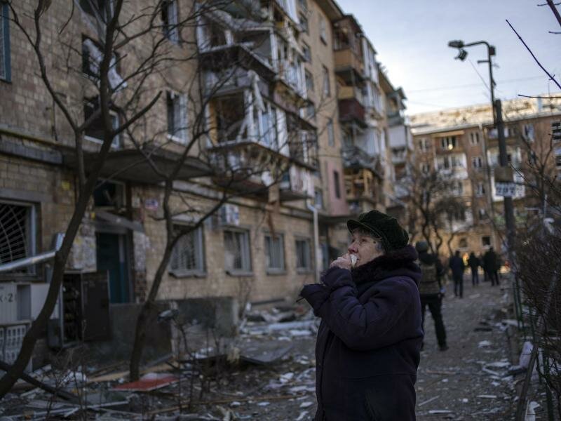 Eine Frau betrachtet ein durch eine Bombe beschädigtes Wohnhaus in Kiew. Foto: Rodrigo Abd/AP/dpa