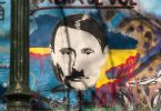 Auf der sogenannten John-Lennon-Mauer in Prag hat ein Unbekannter den russischen Präsidenten Wladimir Putin angesichts des Ukraine-Kriegs als Adolf Hitler dargestellt. Foto: Michael Heitmann/dpa