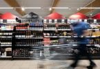 Ein Mann geht mit seinem Einkaufswagen in einem Discounter an Produkten vorbei. Foto: Federico Gambarini/dpa