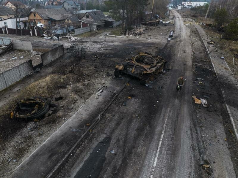Ein Fahrradfaher fährt auf einer Straße in Kiew an einem zerstörten russischen Panzer vorbei. Foto: Rodrigo Abd/AP/dpa