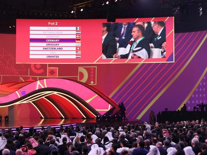Bundestrainer Hansi Flick - im Saal auf einen Monitor gezeigt - verfolgt die Ziehung von Deutschland. Foto: Christian Charisius/dpa