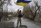 Ein ukrainischer Soldat schwenkt die ukrainische Flagge auf einer Straße in Butscha. Foto: Rodrigo Abd/AP/dpa