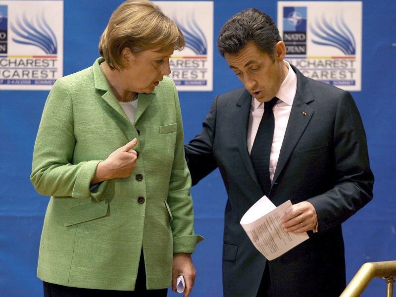Die damalige Bundeskanzlerin Angela Merkel (l, CDU) spricht mit Nicolas Sarkozy, damals Präsident von Frankreich, am Ende der Eröffnungssitzung des NATO-Gipfels. Foto: Robert Ghement/epa/dpa