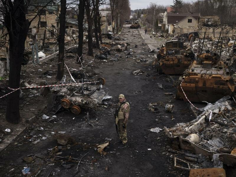 Ein ukrainischer Soldat steht in&nbsp;Butscha neben zerstörten russischen Panzern. Foto: Felipe Dana/AP/dpa