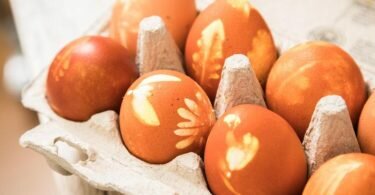 Nach rund 10 Minuten im kochenden Zwiebelschalensud werden die Eier samt Blüten und Blätter aus den Feinkniestrümpfen entfernt. Herauskommen wunderschön natürlich gefärbte Ostereier. Foto: Christin Klose/dpa-tmn