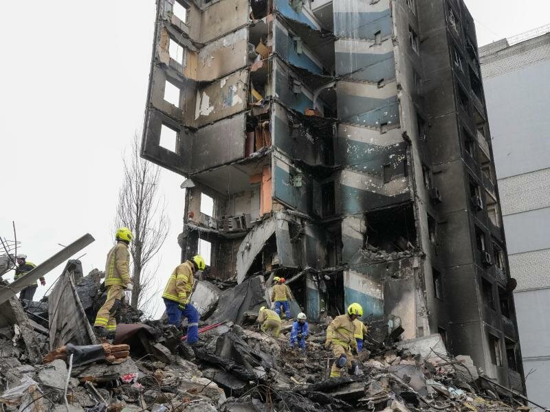 Rettungskräfte stehen in Borodjanka auf den Trümmern eines mehrstöckigen Gebäudes, das durch Beschuss des russischen Militärs zerstört wurde. Foto: Efrem Lukatsky/AP/dpa