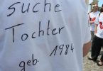 "Suche Tochter, geb. 1984" steht auf dem T-Shirt einer Frau bei einer Kundgebung. Foto: Stephanie Pilick/dpa