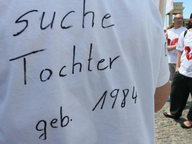 "Suche Tochter, geb. 1984" steht auf dem T-Shirt einer Frau bei einer Kundgebung. Foto: Stephanie Pilick/dpa