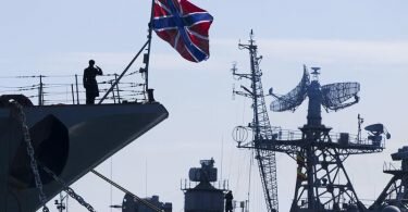 Ein russischer Matrose (l) salutiert am Bug des Raketenkreuzers «Moskwa». Foto: Pavel Golovkin/AP/dpa