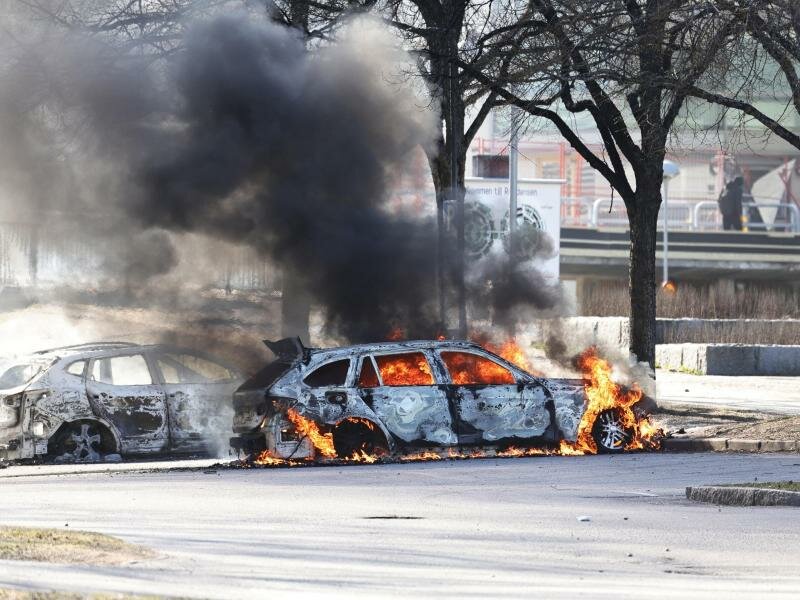 Zwei Autos brennen auf einem Parkplatz während Ausschreitungen. Foto: Stefan Jerrevång/TT NEWS AGENCY/AP/dpa