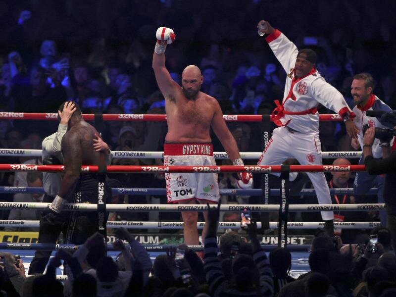 Tyson Fury (3.v.l) feiert vor 94.000 Zuschauern im Wembley-Stadion seinen Sieg über Dillian Whyte (l, vorne). Foto: Ian Walton/AP/dpa
