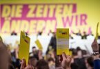 Delegierte halten beim ersten Präsenzparteitag der FDP nach dem Beginn von Corona die Stimmkarten hoch. Foto: Michael Kappeler/dpa
