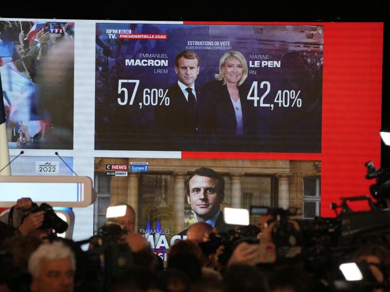 Die ersten Wahlprognosen werden auf einem Bildschirm angezeigt. Foto: Francois Mori/AP/dpa