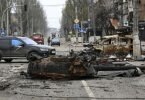 Ein Teil eines zerstörten Panzers und ein verbranntes Fahrzeug auf einer Straße in Mariupol. Foto: Alexei Alexandrov/AP/dpa