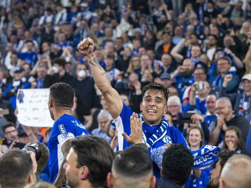 Schalkes Rodrigo Zalazar jubelt mit Fans über den Aufstieg. Foto: David Inderlied/dpa