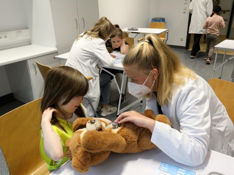 Nach der Wiedereröffnung des Teddybärkrankenhauses an der Universitätsmedizin empfängt Anna Rautmann, Medizinstudentin, den Teddy einer kleinen Besucherin. Foto: Bernd Wüstneck/dpa