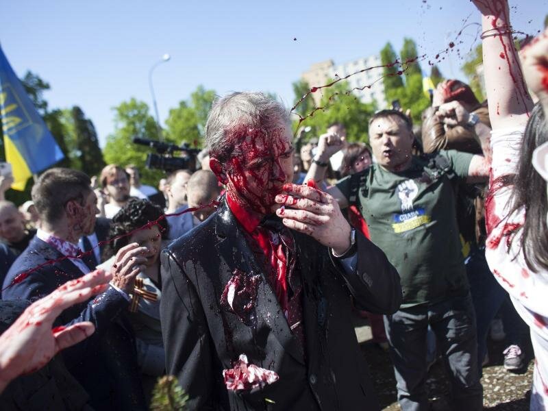 Sergej Andrejew (M.), russischer Botschafter in Polen, wird bei einer Kranzniederlegung auf dem Friedhof für die gefallenen sowjetischen Soldaten im Zweiten Weltkrieg in Warschau von Demonstranten mit roter Farbe bespritzt. Foto: Maciek Luczniewski/AP/dpa