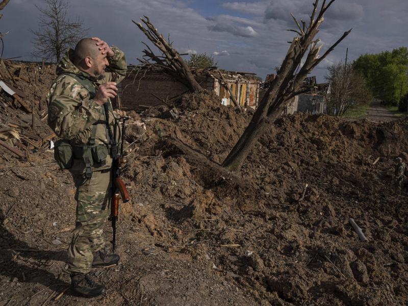 Ein ukrainischer Soldat inspiziert nach einem russischen Luftangriff in Bachmut das Terrain. Foto: Evgeniy Maloletka/AP/dpa