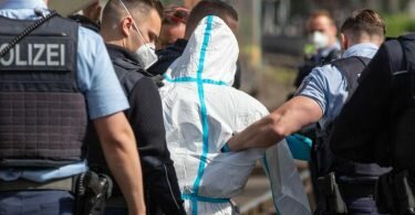 Polizisten führen den mutmaßlichen Täter ab. Der Mann soll in einer Regionalbahn mit einem Messer auf Reisende eingestochen haben. Foto: Ralf Roeger/dpa