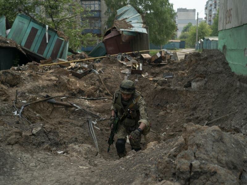 Ein Uniformierter inspiziert einen Krater nach einem Luftangriff der russischen Streitkräfte in der Region Luhansk. Foto: Leo Correa/AP/dpa