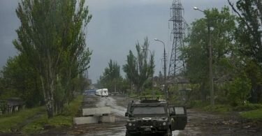 Ein russisches gepanzertes Fahrzeug bewacht die Straße zum belagerten Stahlwerk Azovstal während einer Evakuierung in Mariupol. Foto: Alexander Zemlianichenko/AP/dpa