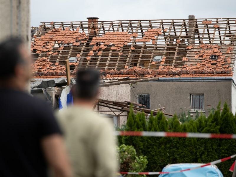 Anwohner blicken auf das beschädigte Dach eines Hauses in Lippstadt. Foto: Friso Gentsch/dpa