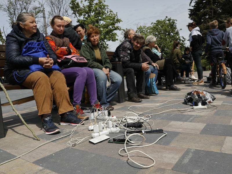 Menschen in Mariupol laden ihre Telefone auf - das Gebiet in der&nbsp;Ostukraine steht unter der Regierung der sogenannten Donezker Volksrepublik. Foto: Alexei Alexandrov/AP/dpa