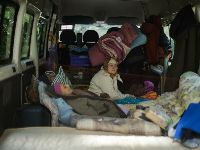 Zwei Frauen sitzen in Bachmut in einem Lieferwagen. Foto: Francisco Seco/AP/dpa