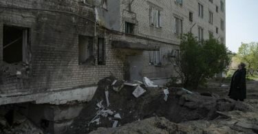 Eine Frau neben dem Krater einer Explosion, die in Lyman eine Wohnung und einen Keller eines Wohnhauses beschädigt hat. Foto: Leo Correa/AP/dpa