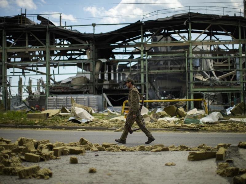 Ein ukrainischer Soldat geht an einer durch Beschuss zerstörten Fabrik vorbei. Foto: Francisco Seco/AP/dpa