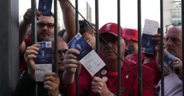 Liverpool-Fans zeigen ihre Eintrittskarten, während sie auf den Einlass ins Stade de France warten. Foto: Christophe Ena/AP/dpa