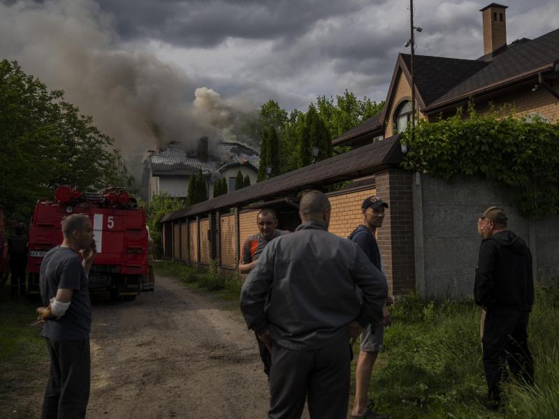 Nachbarn versammeln sich in Charkiw um ein brennendes Haus, das bei einem russischen Angriff mit Streumunition getroffen wurde. Foto: Bernat Armangue/AP/dpa