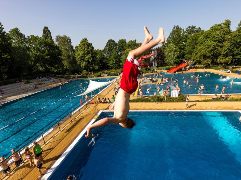 Im Freibad in Forst (Lausitz) springt ein Badegast bei etwa 35 Grad Celsius im Schatten von der 5-meter-Plattform des Sprungturms ins Becken. Foto: Frank Hammerschmidt/dpa