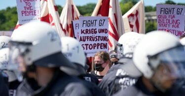 G7-Demonstranten stehen Polizisten auf der Münchener Theresienwiese gegenüber. Foto: Michael Kappeler/dpa