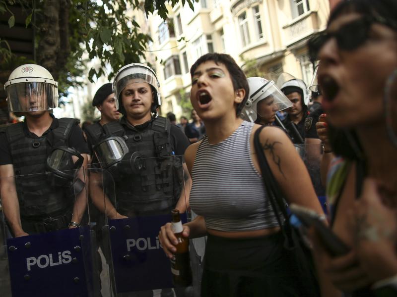 Teilnehmende der Pride-Parade in Istanbul stehen neben Polizisten und rufen Slogans. Foto: Emrah Gurel/AP/dpa