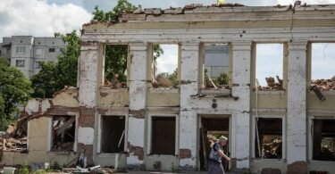 Eine Frau geht an den Ruinen der Stadtverwaltung von Ochtyrka vorbei. Foto: Michal Burza/ZUMA Press Wire/dpa