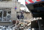Zwei Feuerwehrleute beseitigen die Trümmer nach einem russischen Raketenangriff auf eine Schule in Charkiw. Foto: Ukraine-Krieg-Ort