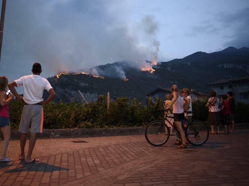 In Italien brennt es vielerorts aufgrund der Trockenheit: Einheimische beobachten, wie das Feuer am zweiten Tag der Brände in Nago (Südtirol) die Vegetation vernichtet. Foto: Aleksander Kalka/ZUMA Press Wire/dpa